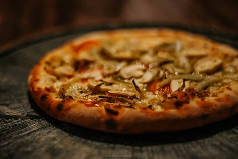 Close de pizza de calabresa com queijo derretido na pizzaria da Serra Gaúcha.'