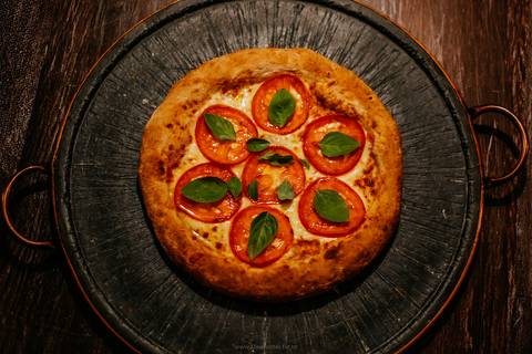 Foto de ingredientes frescos usados ​​em pizzaria na Serra Gaúcha, como tomate e manjericão.'