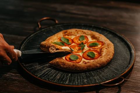 Detalhe da textura e crocância da massa de pizza na pizzaria de Bento Gonçalves.'