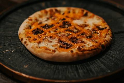 Fotografia de pizza de quatro queijos com borda recheada em pizzaria local.'