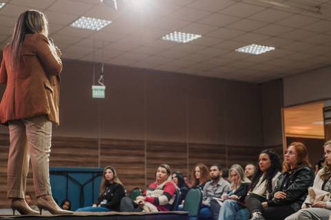 Palestrante falando sobre iluminação natural para ensaios newborn.
'
