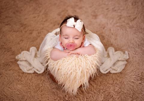 Rosto delicado do bebê, com luz suave realçando suas feições.'