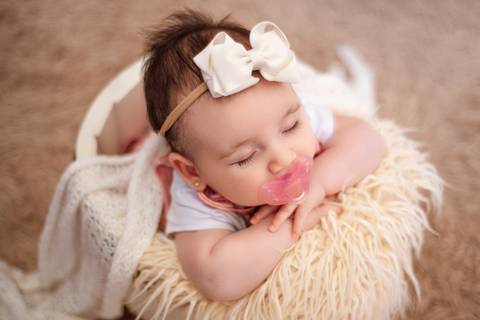 Bebê adormecido, capturado em uma posição de segurança e conforto.'