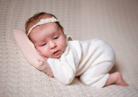 Bebê dormindo em manta aconchegante durante o ensaio newborn.'