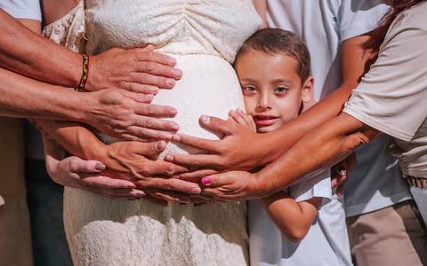 amília grávida em sessão fotográfica no bosque de pinheiros, Farroupilha: crianças colhendo flores silvestres enquanto a gestante observa com carinho'