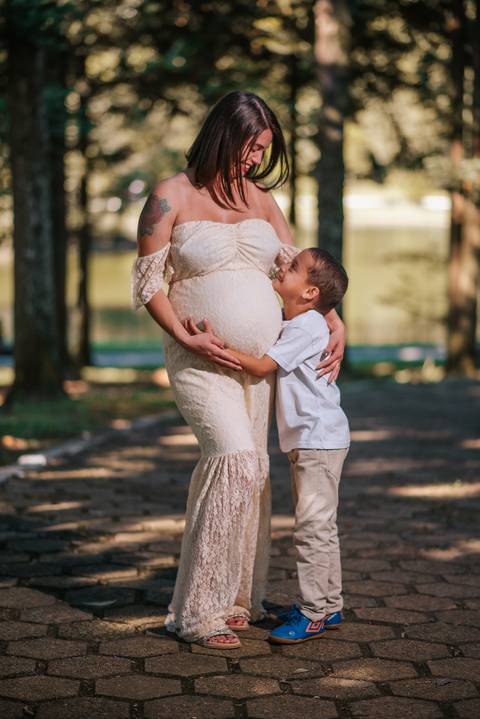 Ensaio gestante à beira do lago artificial do Parque dos Pinheiros, Farroupilha: grávida abraçando filhos em momento de conexão e amor'