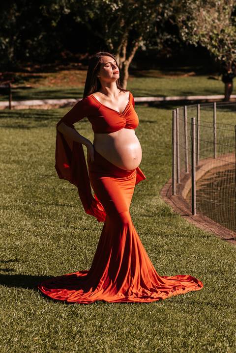 Gestante em pose delicada no coreto do Parque dos Pinheiros, Farroupilha: registro artístico com arquitetura histórica e luz dourada do pôr do sol'