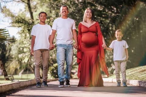 Família grávida sorrindo sob os pinheiros do Parque dos Pinheiros, Farroupilha: ensaio gestante com cenário natural e luz suave do entardecer'