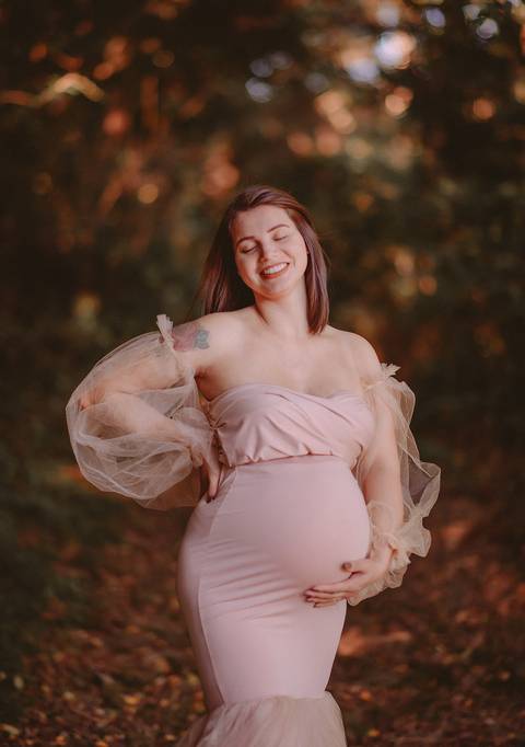 Gestante sorrindo segurando a barriga em ensaio ao ar livre em Farroupilha, RS'