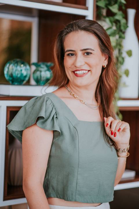 Close de mulher usando blusa verde e joias delicadas, olhando com expressão serena.

'