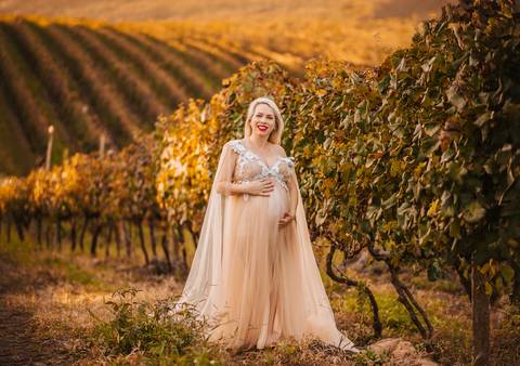 Cena em contraluz com a barriga iluminada pelo pôr do sol. Imagem simbólica de conexão entre mãe e filho.'