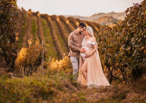 Retrato espontâneo com a gestante sorrindo em meio às folhas secas, celebrando o agora.'