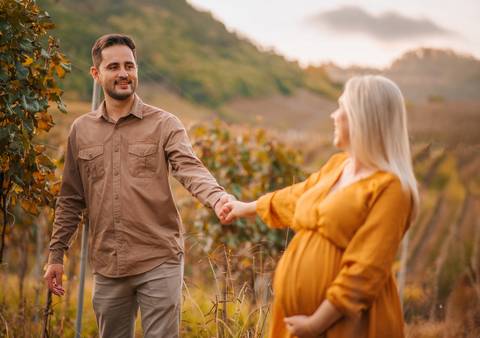 Vestido dourado formando asas ao redor da gestante. Imagem forte de empoderamento e amor próprio.'
