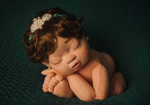 Boneca reborn Jolie em pose frontal com braços cruzados, exemplo usado em aulas e treinamentos sobre fotografia de recém-nascidos.'