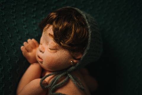 Boneca reborn Jolie em pose lateral clássica, usada para treinamento de ensaio newborn por fotógrafa especializada em recém-nascidos na Serra Gaúcha.'