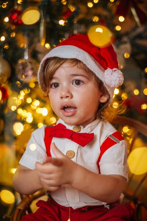 Ensaio natalino infantil com Evan em cenário iluminado.'