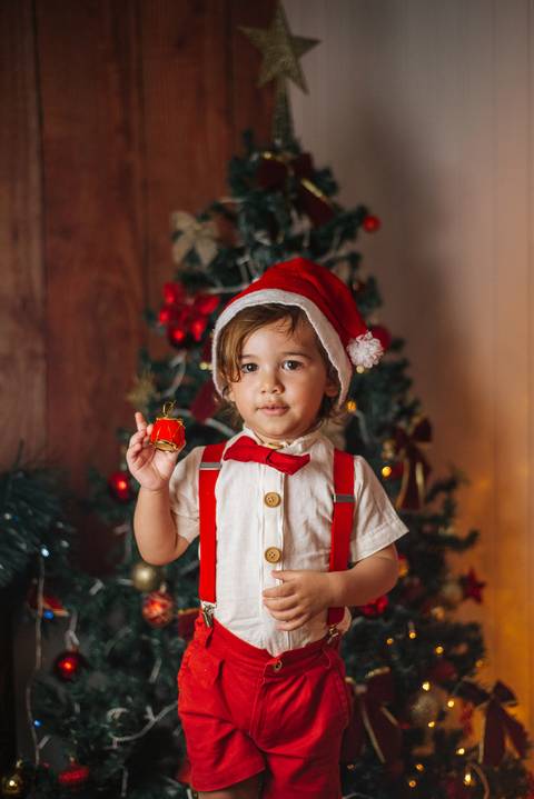 Bebê deitado em mini trenó natalino.'