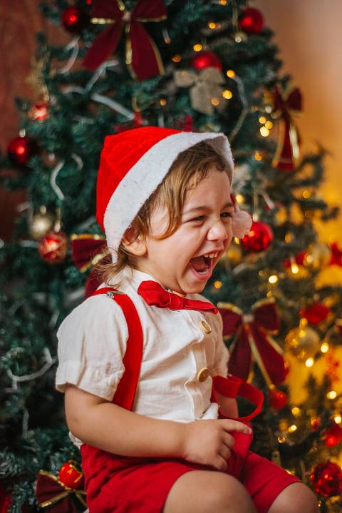 Foto de gestante com elementos dourados no cenário de Natal.'