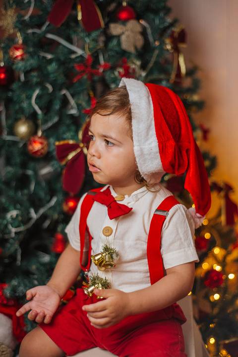 Casal sentado ao lado da árvore em ensaio natalino.'