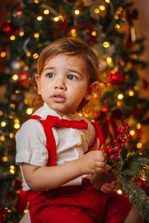 Ensaio de Natal intimista em casa com luzes amareladas.'
