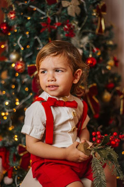 Foto temática de Natal com crianças na sala decorada.'