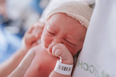 Bebê recém-nascida com pulseira de identificação hospitalar após o parto, cobertura fotográfica de nascimento em Bento Gonçalves.'