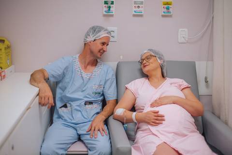 Casal aguardando o nascimento da filha em quarto hospitalar no Hospital Tacchini, cobertura fotográfica de parto cesariana.'