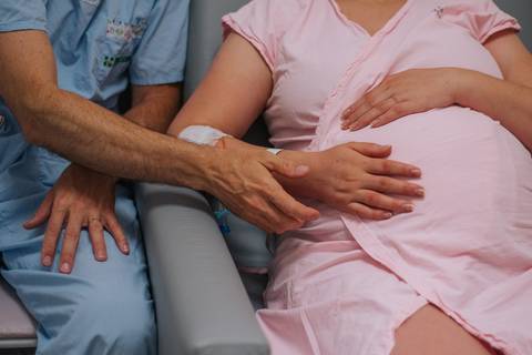 Toque dos pais na barriga da gestante momentos antes do parto, fotografia de nascimento em Bento Gonçalves RS.'