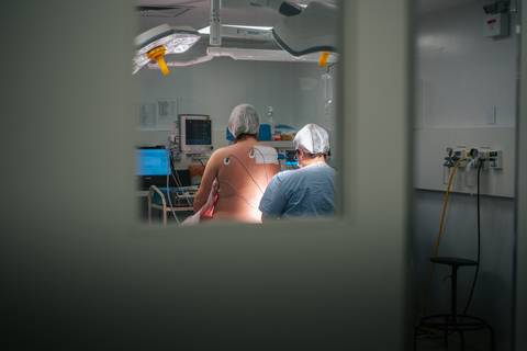 Equipe médica preparando a sala cirúrgica para parto cesariana no Hospital Tacchini, cobertura fotográfica de nascimento.'