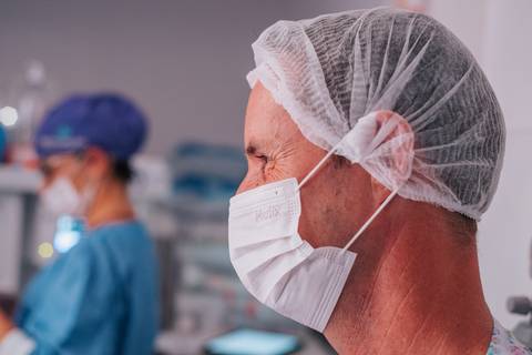 Pai acompanhando os primeiros momentos da filha após o nascimento, fotografia de parto emocional.'