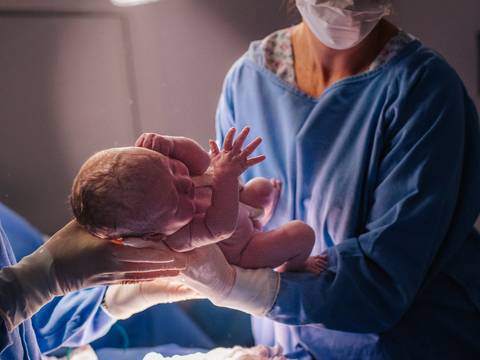 Momento de aproximação entre mãe e bebê após cesariana, cobertura fotográfica de parto.'