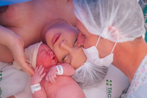 Contato pele a pele entre mãe e bebê após o parto cesariana, cobertura fotográfica de nascimento hospitalar.'