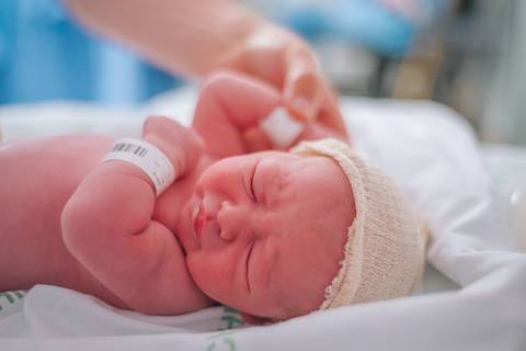 Recém-nascida acomodada após o nascimento, fotografia de parto no Hospital Tacchini.'