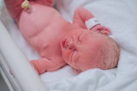 Recém-nascida descansando após o nascimento, fotografia de parto hospitalar.'