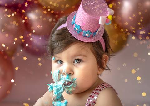Bebê durante ensaio Smash the Cake explorando o bolo, mãos sujas de cobertura, fotografia infantil espontânea em estúdio.'