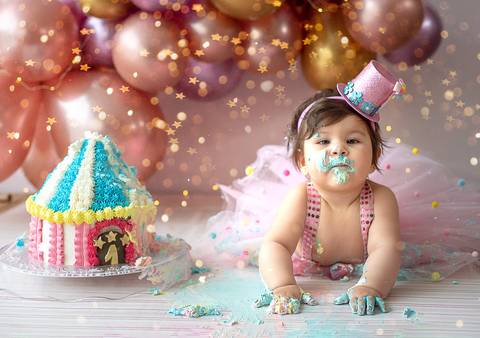 Bebê sentada em ensaio Smash the Cake com bolo decorado, cenário suave e composição pensada para fotografia infantil.'