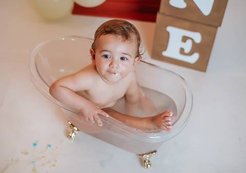 Bebê sorrindo dentro da banheira no ensaio Smash the Cake, fotografia infantil que registra diversão após o bolo.'