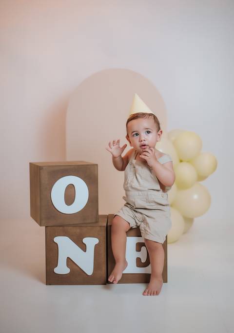 Ensaio de 1 ano com bebê usando chapéu de aniversário em estúdio fotográfico'