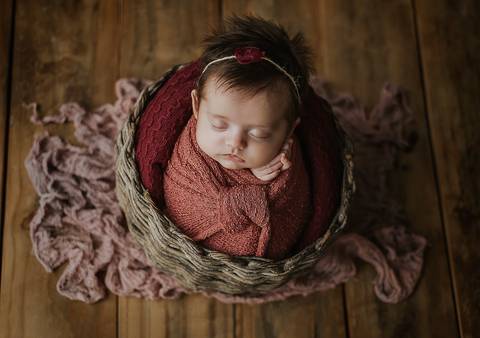 Bebê de 3 meses em ensaio old newborn acomodada em cesto com apoio seguro, cenário neutro em estúdio'