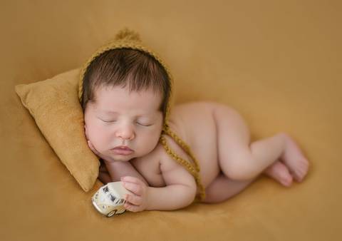 Fotografia newborn de recém-nascido deitado de lado, ensaio realizado nos primeiros dias de vida em estúdio'
