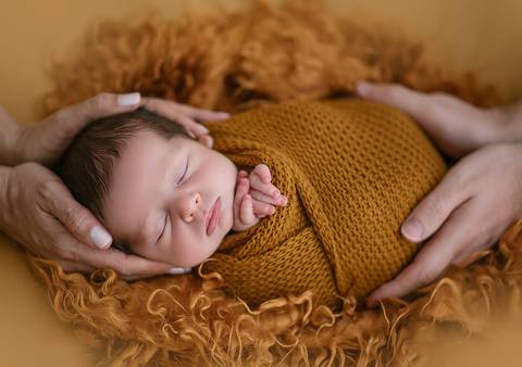 Ensaio newborn tradicional com bebê recém-nascido envolto em manta, fotografia profissional em estúdio'
