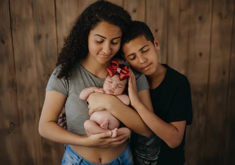 Ensaio newborn tradicional com bebê recém-nascida no colo da mãe, close afetivo em estúdio'