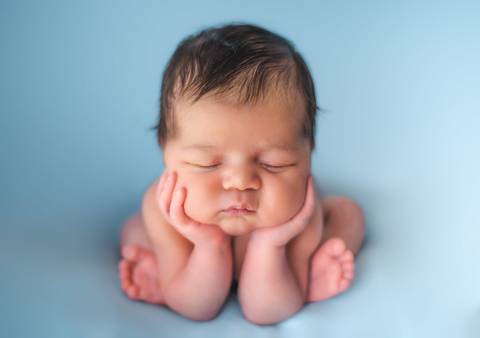 Ensaio newborn tradicional com bebê recém-nascido em fundo azul claro, pose clássica com condução técnica'