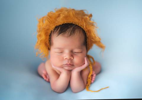 Ensaio newborn tradicional com bebê recém-nascido em cenário azul, posição confortável e segura'