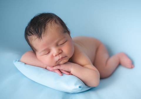 Bebê recém-nascido em ensaio newborn clássico, posição de bruços adaptada e segura'