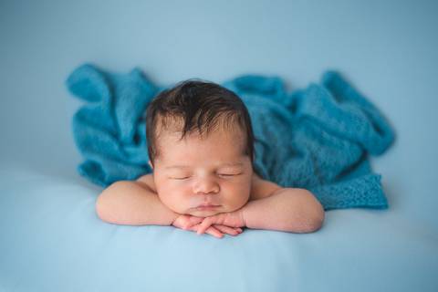 Ensaio newborn tradicional com bebê recém-nascido em cenário minimalista, pose confortável respeitando o período ideal'