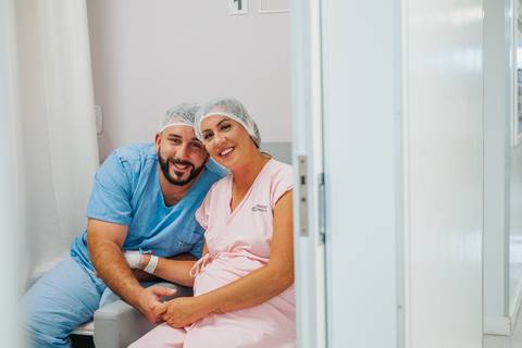 Pai e mãe juntos no quarto hospitalar após o nascimento do bebê, em momento de conexão e alívio pós-parto.'