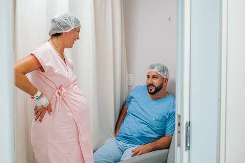 Mãe em trabalho de parto conversando com o pai do bebê no Hospital Tacchini, momentos antes do nascimento.'