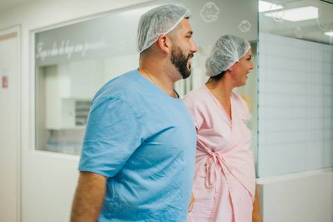 Pai acompanhando o trabalho de parto da esposa em ambiente hospitalar, aguardando a chegada do filho.'