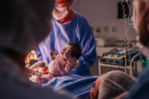 Equipe médica realizando os procedimentos iniciais com o recém-nascido logo após o parto hospitalar.'
